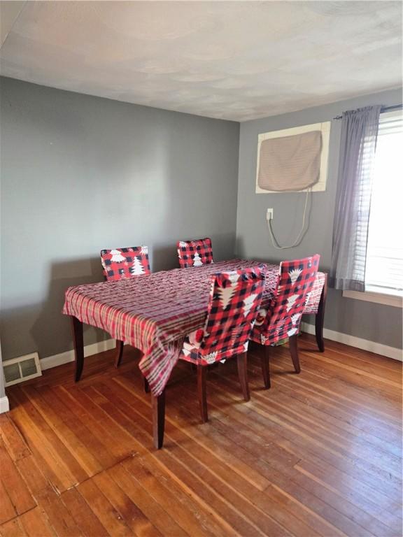 dining room with hardwood / wood-style floors, visible vents, and baseboards