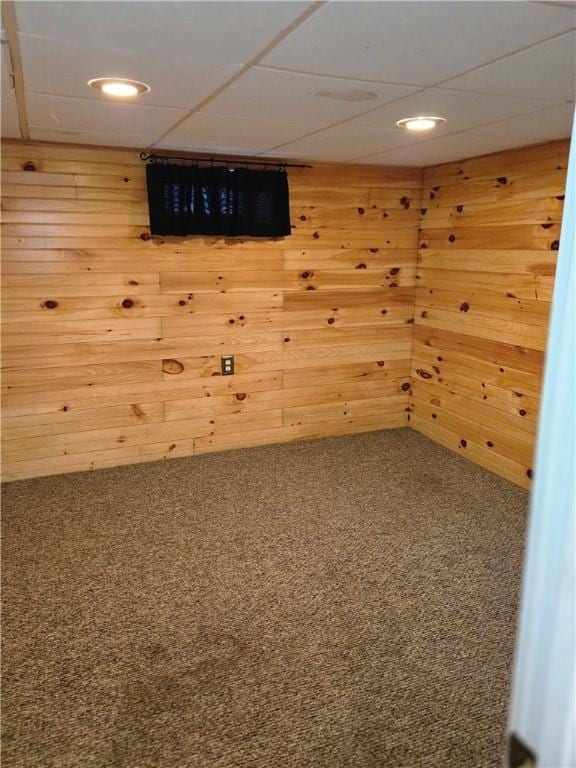 carpeted empty room featuring wooden walls