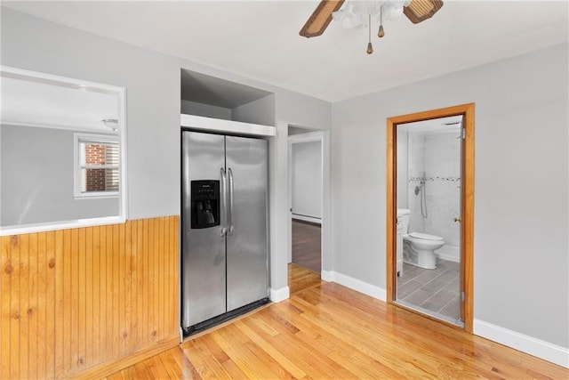 unfurnished bedroom featuring a closet, baseboard heating, ensuite bathroom, light wood-type flooring, and stainless steel fridge