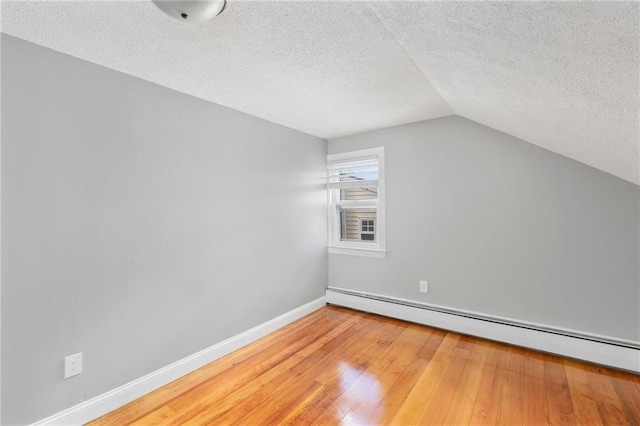 bonus room featuring baseboard heating, vaulted ceiling, a textured ceiling, baseboards, and hardwood / wood-style flooring