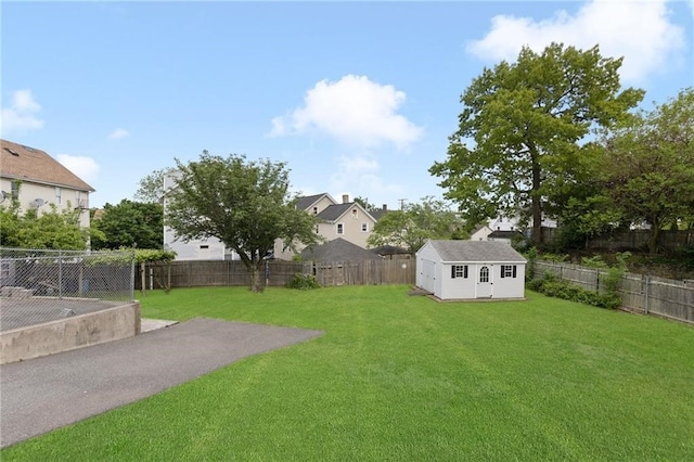 view of yard with a storage shed, a fenced backyard, and an outbuilding