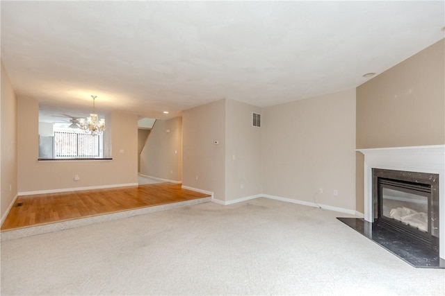 unfurnished living room featuring baseboards, visible vents, carpet flooring, a fireplace, and a chandelier