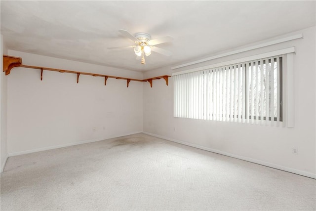 empty room featuring carpet floors, a ceiling fan, and baseboards