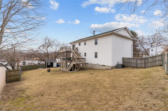 back of property with a storage shed, a lawn, a fenced backyard, stairs, and an outdoor structure