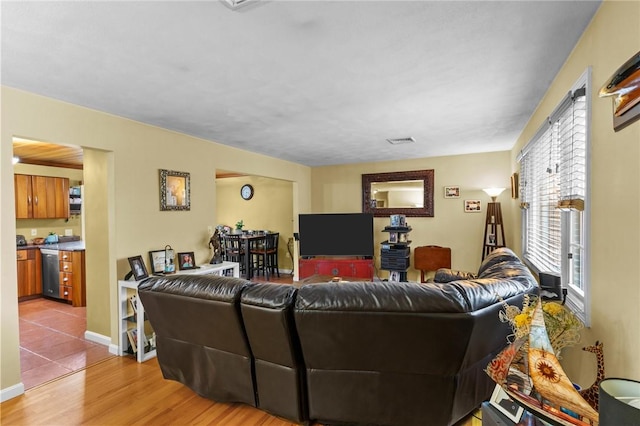 living room featuring light wood-type flooring, visible vents, and baseboards