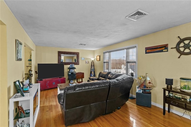 living area featuring wood finished floors, visible vents, and baseboards