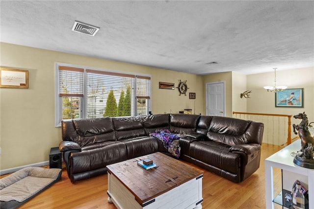 living room with a chandelier, light wood finished floors, and visible vents