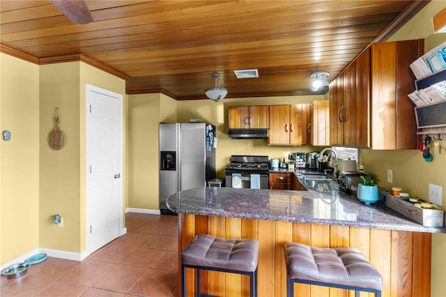 kitchen with brown cabinets, tile patterned floors, a peninsula, stainless steel appliances, and a sink