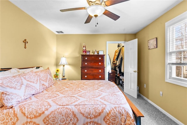 carpeted bedroom with a spacious closet, multiple windows, visible vents, and baseboards