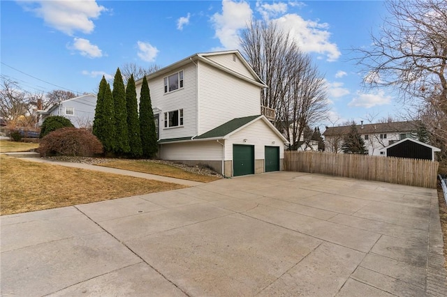 view of side of property with an attached garage, fence, and concrete driveway