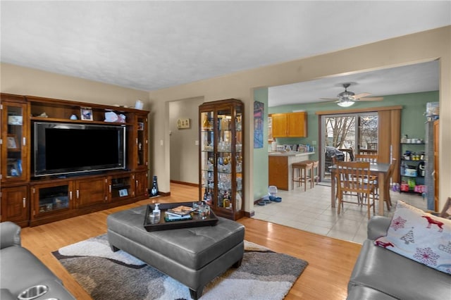 living room with light wood-style flooring, baseboards, and a ceiling fan