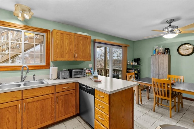 kitchen featuring light countertops, brown cabinetry, a sink, dishwasher, and a peninsula