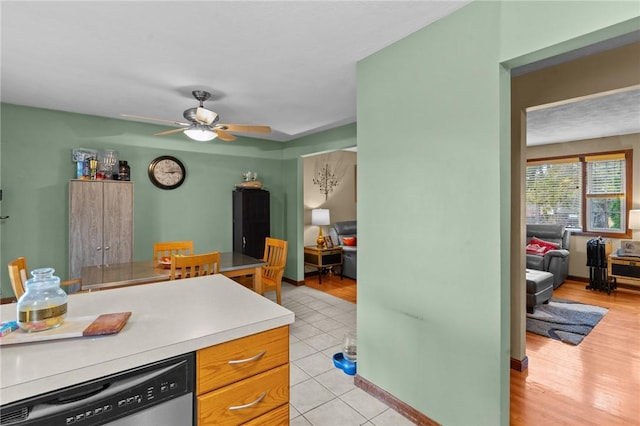 kitchen with light tile patterned floors, light countertops, ceiling fan, dishwasher, and baseboards