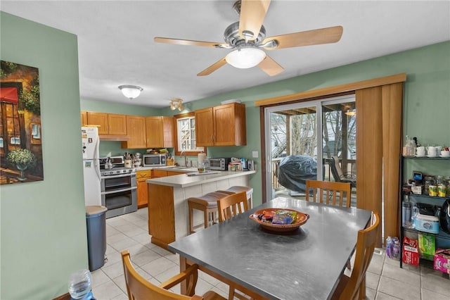 kitchen featuring light tile patterned flooring, a peninsula, a sink, a healthy amount of sunlight, and appliances with stainless steel finishes