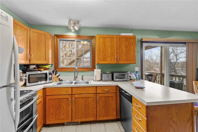 kitchen with stainless steel appliances, light countertops, a sink, and a peninsula