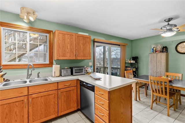 kitchen featuring a toaster, dishwasher, a peninsula, light countertops, and a sink