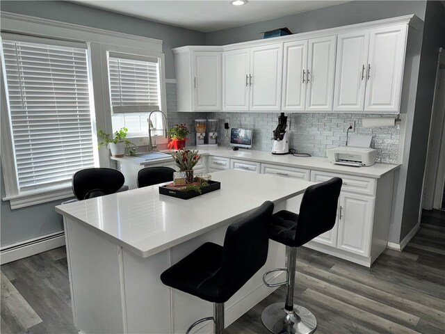 kitchen with backsplash, a kitchen island, white cabinets, and wood finished floors