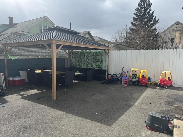 view of vehicle parking featuring a gazebo, a carport, and a fenced backyard