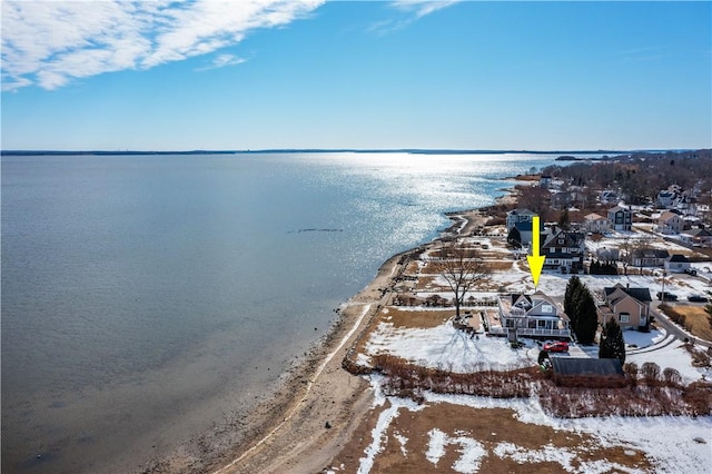 snowy aerial view featuring a water view and a residential view