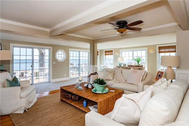 living area featuring ornamental molding, beamed ceiling, ceiling fan, and wood finished floors