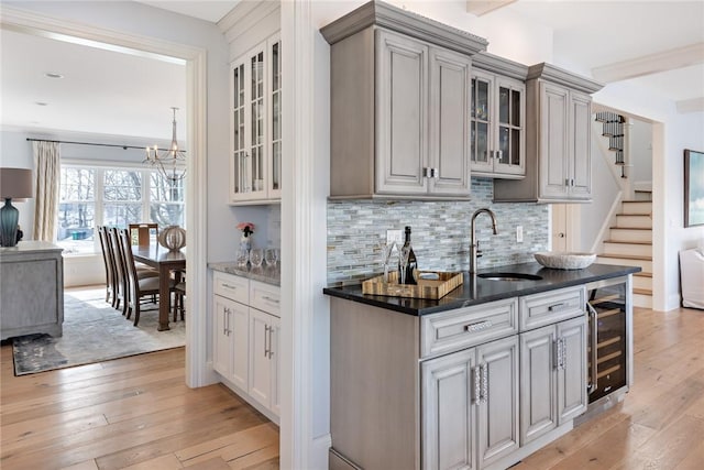 bar with tasteful backsplash, wine cooler, a sink, and light wood-style floors