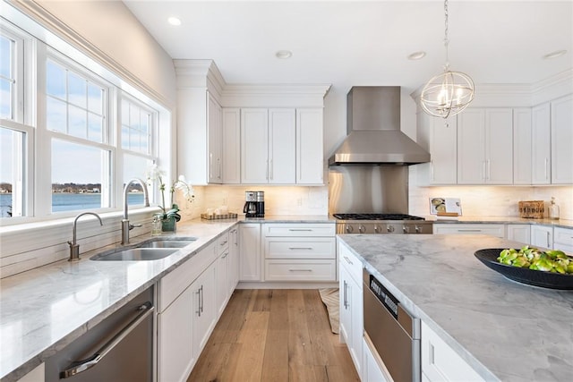 kitchen featuring stainless steel appliances, light wood-style floors, white cabinetry, a sink, and wall chimney exhaust hood