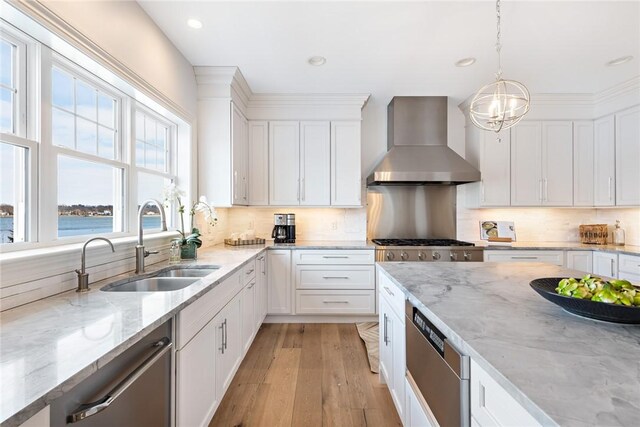 1040 Buttonwoods Ave, Warwick, RI 02886 - kitchen with wall chimney range hood, a sink, appliances with stainless steel finishes, light wood finished floors, and white cabinetry