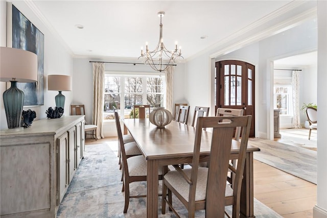 dining space featuring light wood-style floors, ornamental molding, and an inviting chandelier