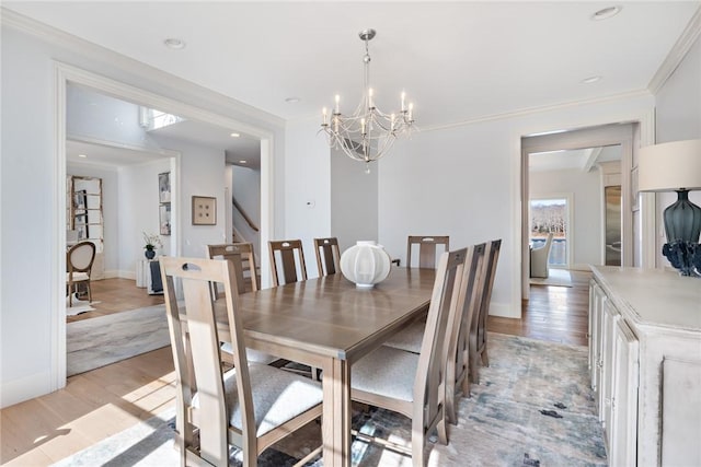 dining area featuring baseboards, light wood finished floors, an inviting chandelier, and crown molding