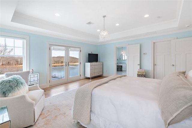 bedroom with access to outside, a raised ceiling, light wood finished floors, and french doors