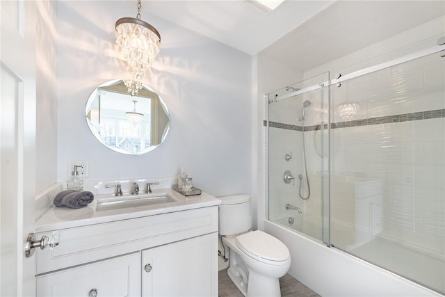 bathroom with toilet, an inviting chandelier, shower / bath combination with glass door, and vanity