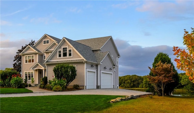 view of front of property featuring a garage, driveway, a front lawn, and roof with shingles