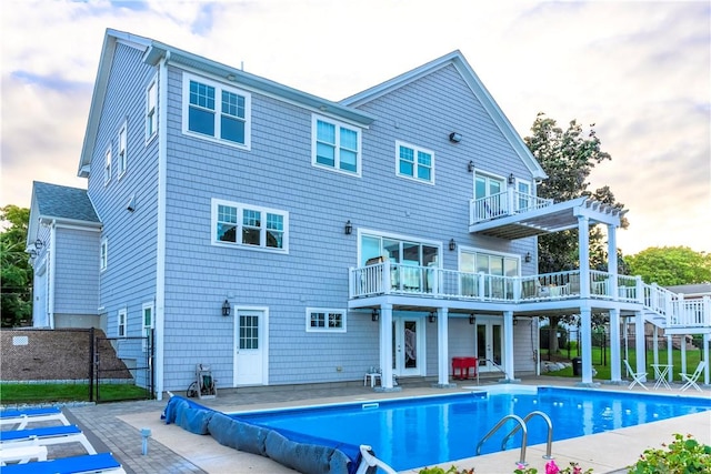 rear view of property featuring a balcony, fence, french doors, a fenced in pool, and a patio area