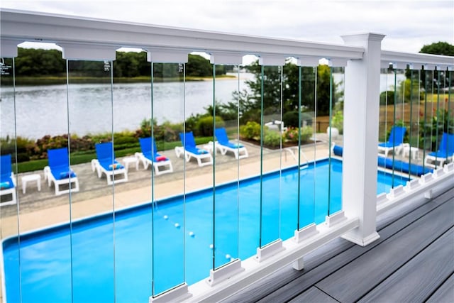 outdoor pool with a water view and a patio