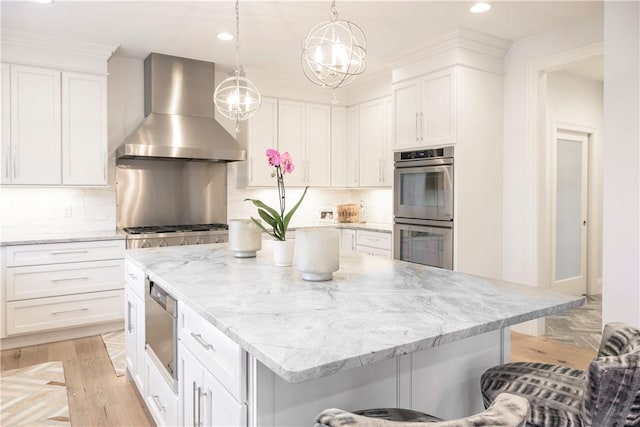 kitchen featuring wall chimney exhaust hood, decorative backsplash, white cabinets, and stainless steel double oven