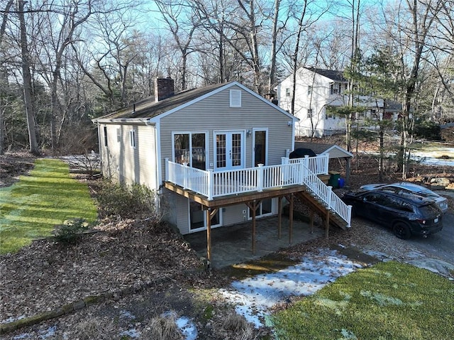 back of property featuring a wooden deck, french doors, a chimney, and stairway