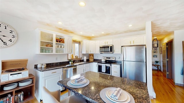 kitchen with dark stone countertops, recessed lighting, appliances with stainless steel finishes, white cabinets, and a sink