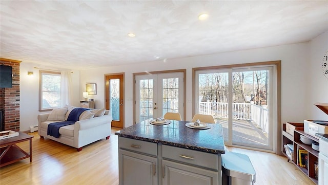 kitchen featuring a kitchen island, gray cabinets, light wood-style floors, french doors, and dark countertops