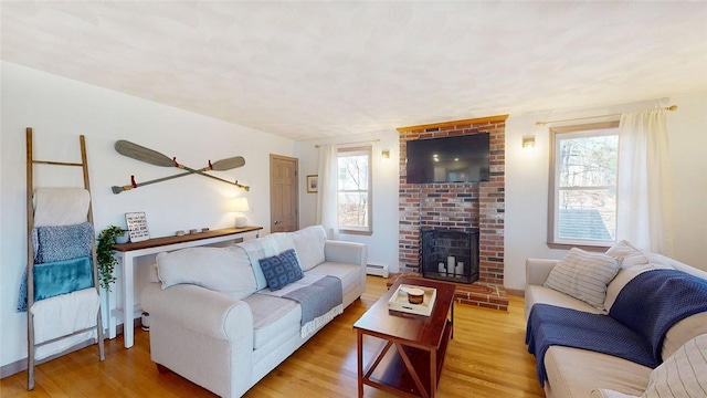 living area featuring wood finished floors, a healthy amount of sunlight, and a baseboard radiator