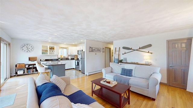 living room featuring recessed lighting, light wood-type flooring, and a baseboard heating unit