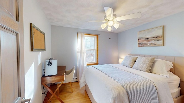 bedroom featuring a baseboard heating unit, a ceiling fan, and light wood-type flooring