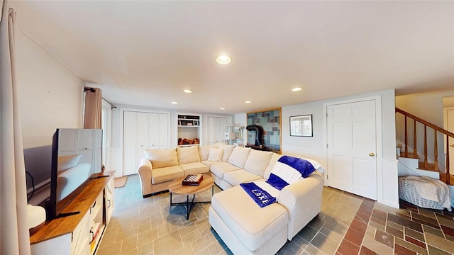 living room with stairway, recessed lighting, and a wood stove