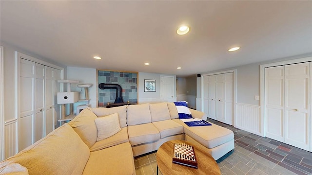 living area featuring a wainscoted wall, recessed lighting, a wood stove, and stone finish floor