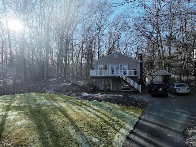 exterior space with a lawn, a deck, driveway, stairway, and a chimney