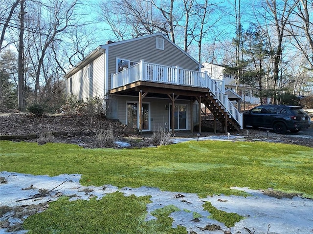 rear view of house featuring stairway, a lawn, and a wooden deck