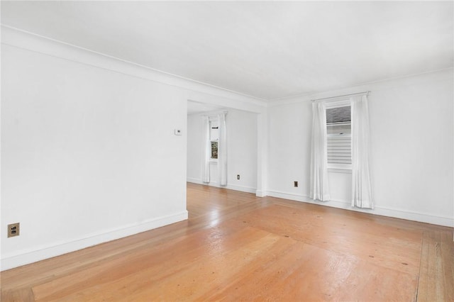 spare room with baseboards and wood finished floors