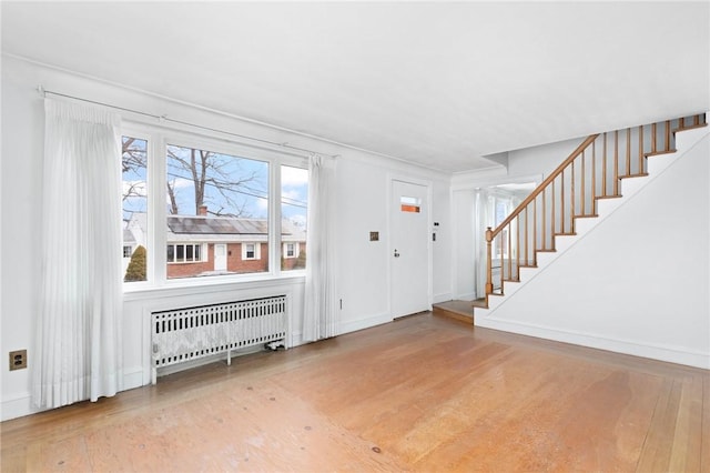 entrance foyer featuring wood finished floors, radiator heating unit, and stairs