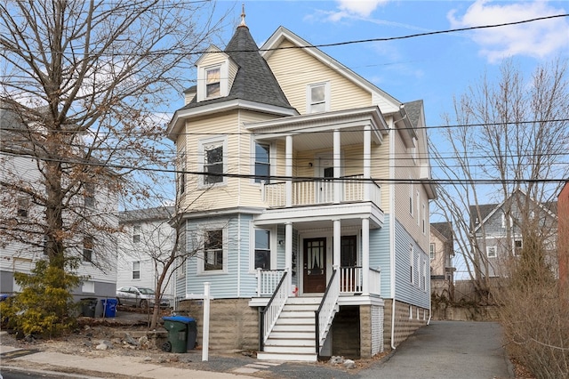 victorian-style house featuring a shingled roof, a porch, and a balcony