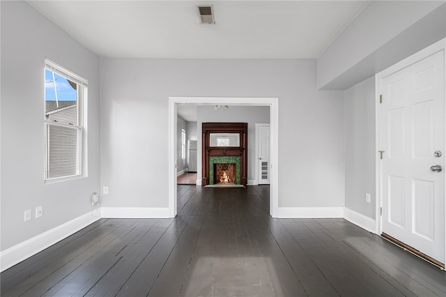 foyer with dark wood-style floors, a warm lit fireplace, visible vents, and baseboards