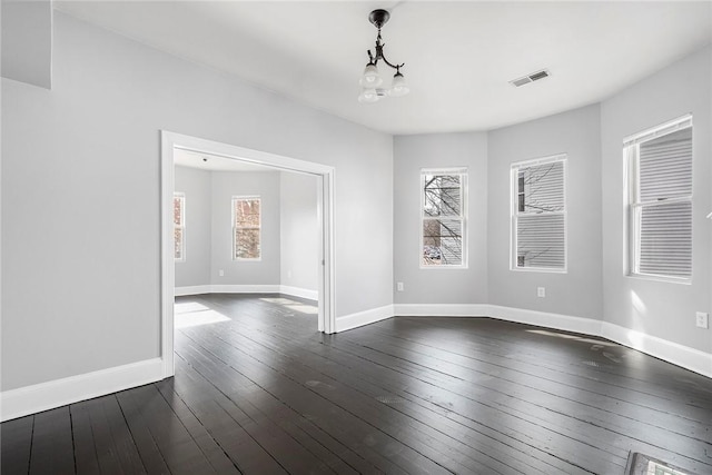 spare room featuring dark wood-style floors, visible vents, baseboards, and an inviting chandelier